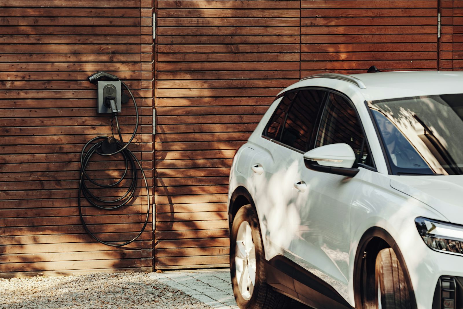 Carro elétrico a carregar numa wallbox instalada na parede exterior de uma moradia