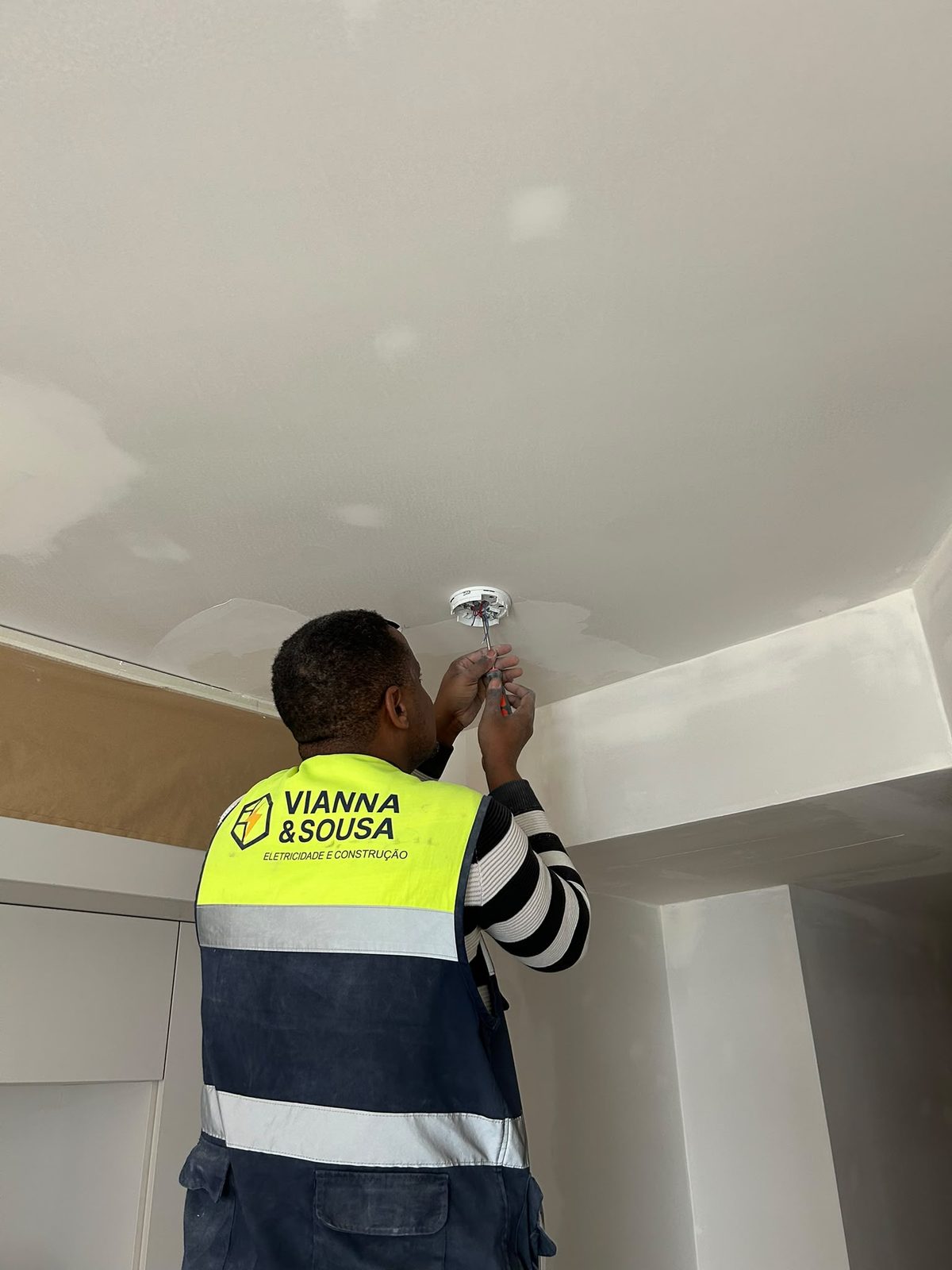 Eletricista da Vianna&Sousa a instalar iluminação em teto durante remodelação residencial